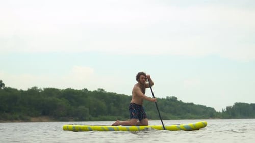Man Paddling on a Paddle Board on River