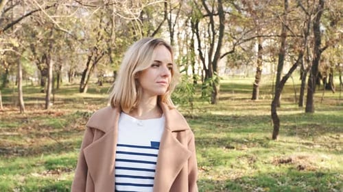 Portrait of Young Attractive Blonde Woman Walking in the Autumn Park on Sunset