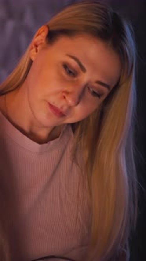 Woman Looks at Daughter Reading Book on Bed at Night