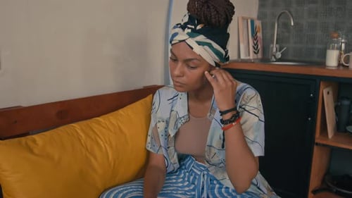 Woman Inserts Wireless Earbud at Home with Laptop