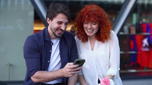 Smiling Couple Looking at Phone in Urban Setting