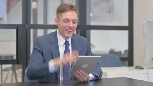 Enthusiastic Businessman Celebrating Success Using Tablet
