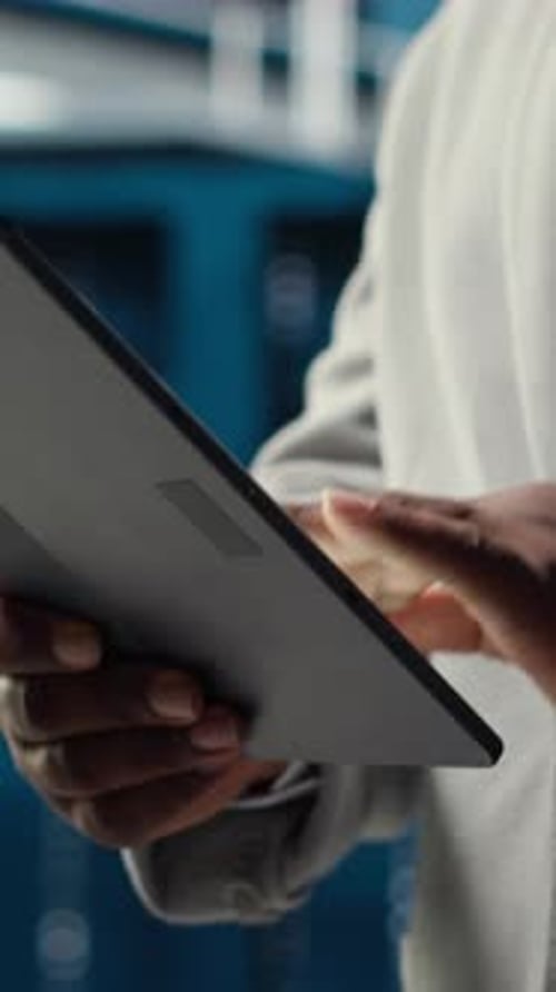 Vertical Video Close Up of System Administrator Walking in Data Center Using Tablet