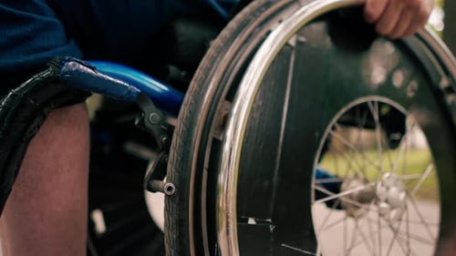 A man performs rides in a wheelchair and presses the brake lever in a city park active lifestyle