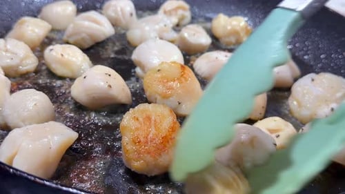 Slow motion closeup home cooking of scallops for new year eve dinner, turning the scallops