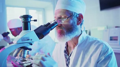 Senior Scientist Using Microscope in Bright Laboratory