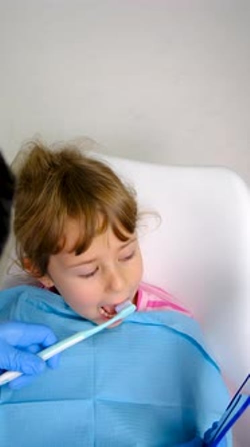 Girl Brushing Teeth in Dental Chair Close Up