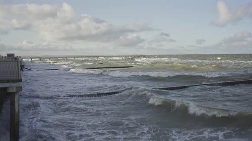 Waves Crashing on Shore with Pier in Distance