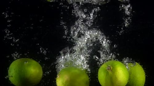 Green Limes Falling Into Water with Bubbles