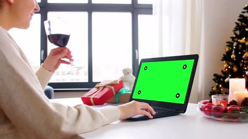 Woman with wine using laptop with green screen