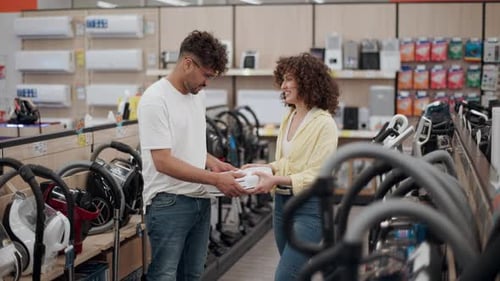 Couple choosing vacuum cleaner in electronics store in slow motion