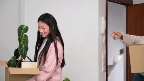 Happy friends entering their new home carrying cardboard boxes