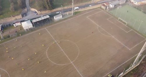 Countryside dusty soccer field aerial view panorama. Children age 14-15 soccer match close to a trai