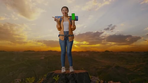 Asian Female Hiker Showing Mock Up Green Screen Smartphone On The Top Of Mountain