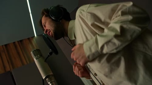 singer with headphones and microphone emotionally recording a new song in a professional studio