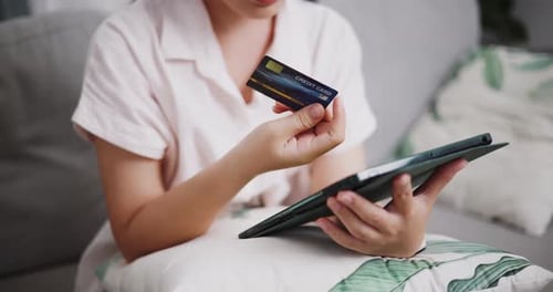 Woman Using Tablet and Credit Card Indoors