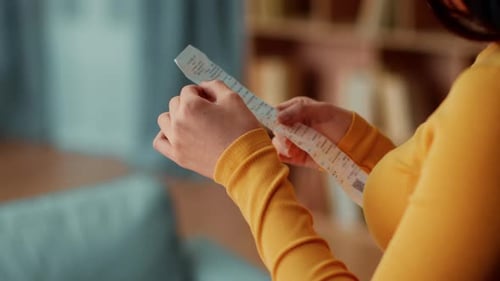 Woman in a Yellow Sweater Holds a Note While Sitting in a Cozy Room With Blue Decor