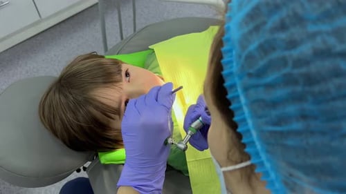A Doctor Dentist in a Medical Mask and Blue Rubber Gloves Puts a Seal on a Little Boy Toddler Dental
