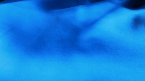 Blue silk fabric waving in the wind. Abstract waves background made of natural silk.