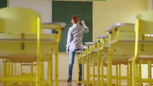 Woman Writing Math Equations on Chalkboard in Classroom