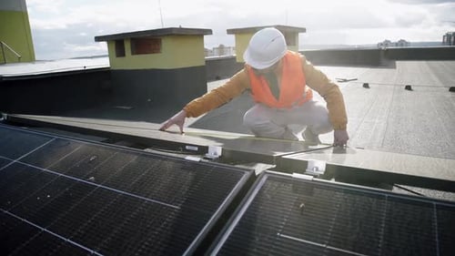 Man Inspecting Solar Panels on Roof