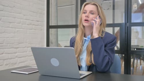Woman Talking on Phone While Working at Desk