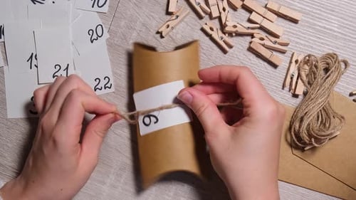 Unrecognizable Young Woman Sticks Number on Craft Bag Fastens with Clothespin Female Making Kraft