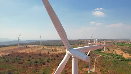 Aerial drone shot flying outdoors above the wind turbine field.