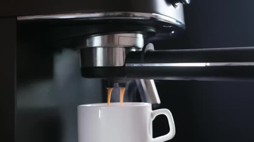 Home Espresso Making Process Coffee Stream Pouring From Machine Into Ceramic Cup