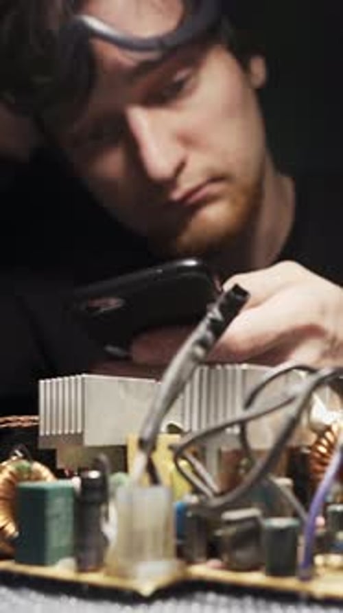 Young Adult Working On Electronic Circuit Board at Night