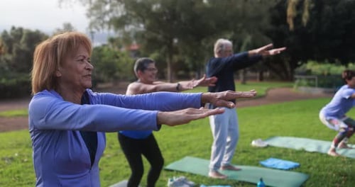 Senior people doing yoga exercises outdoor with city park in background - Healthy lifestyle