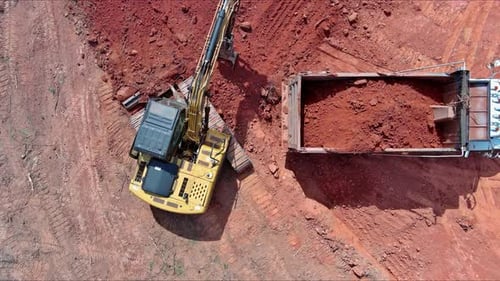 Construction Site Excavator Loads Earth Into Dump Truck Preparing Area for Built Home