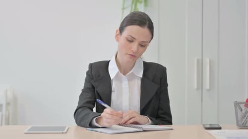 Young Businesswoman Writing while Sitting in Office