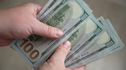Close-up of men's hands counting stack of hundred-dollar US banknotes.