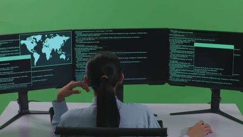 Back View Of Bored Asian Woman Developer Write Code With Multiple Computer Screens In Green Screen