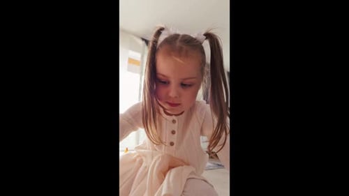 A Young Girl in a Flowing White Dress is Joyfully Engaged in Delightful and Creative Playtime