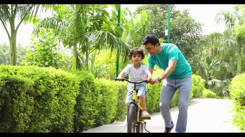Father Teaching Son to Ride Bicycle in Park