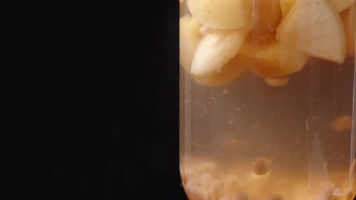 Un pot de compote de pommes et de grenade sur fond noir en gros plan, rotation.