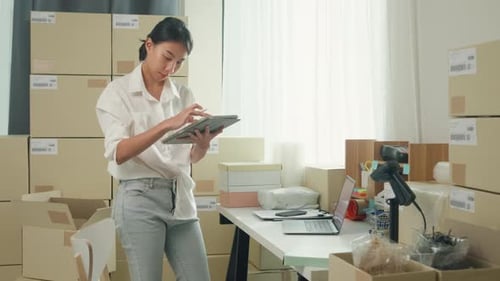Woman Using Tablet Surrounded by Shipping Boxes