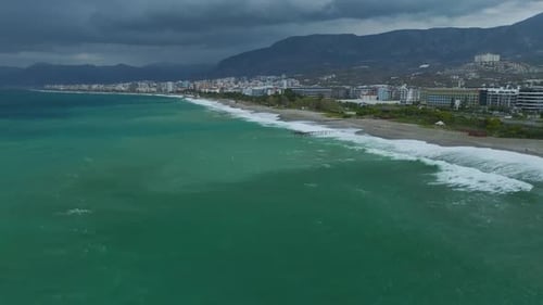 Aerial Video of Coastal City Skyline With Hillside Residences Overlooking Blue Sea and White Waves