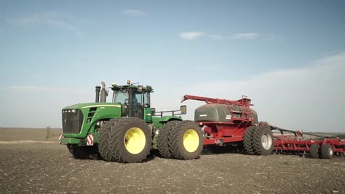 Green tractor seeding wheat on the field
