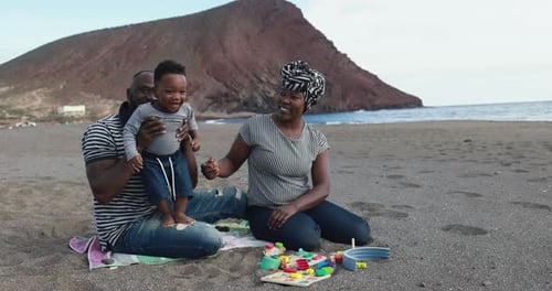 African Child Having Fun with Mother and Father on the Beach -