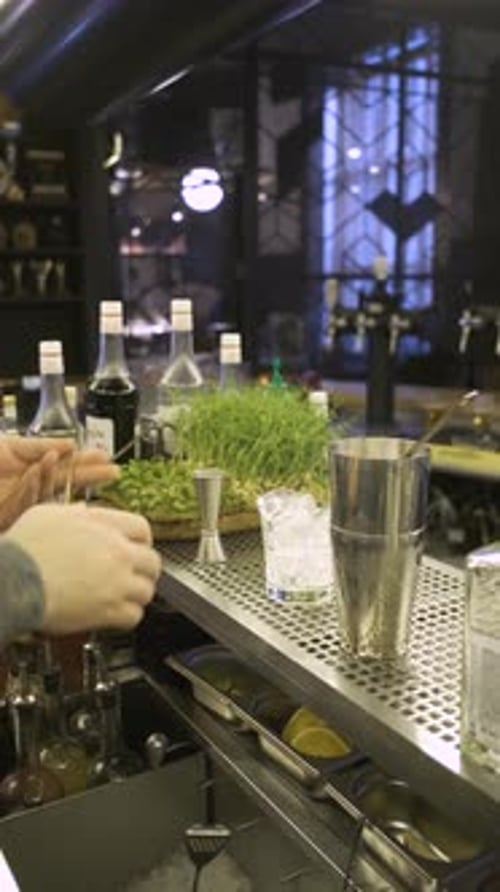 vertical video, close-up of a bartender making a cocktail with ice