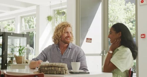Happy diverse couple drinking coffee and talking at a table in cafe