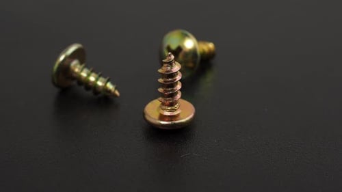 Metal screws on a black background. Rotating screws for driving into plastic.