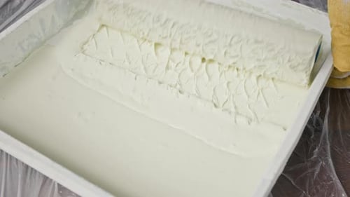 Close-up of Unknown Person Covering Roller Brush in Thick White Paint