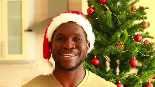 Smiling Man in Santa Hat Near Christmas Tree