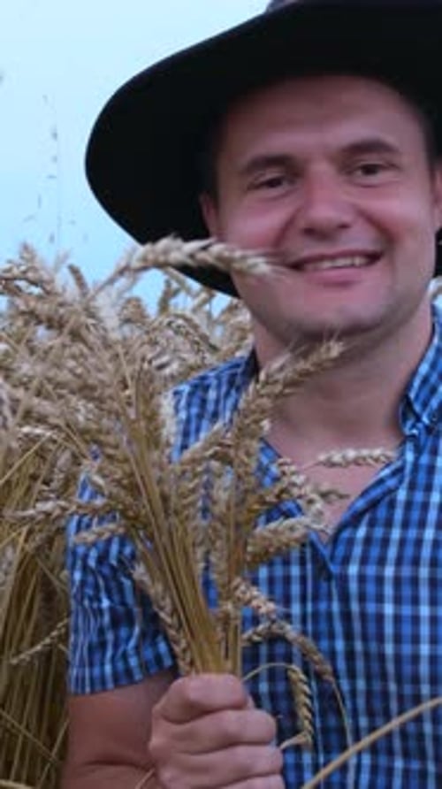 Man Holding Wheat in the Middle of Farm Field
