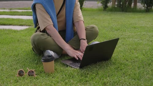 Positive Freelancer Working on Laptop in Park While Sitting on Lawn