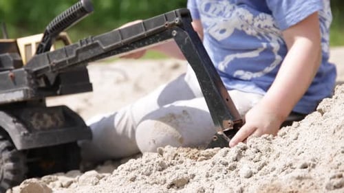 Young boy playing with excavator toy close up